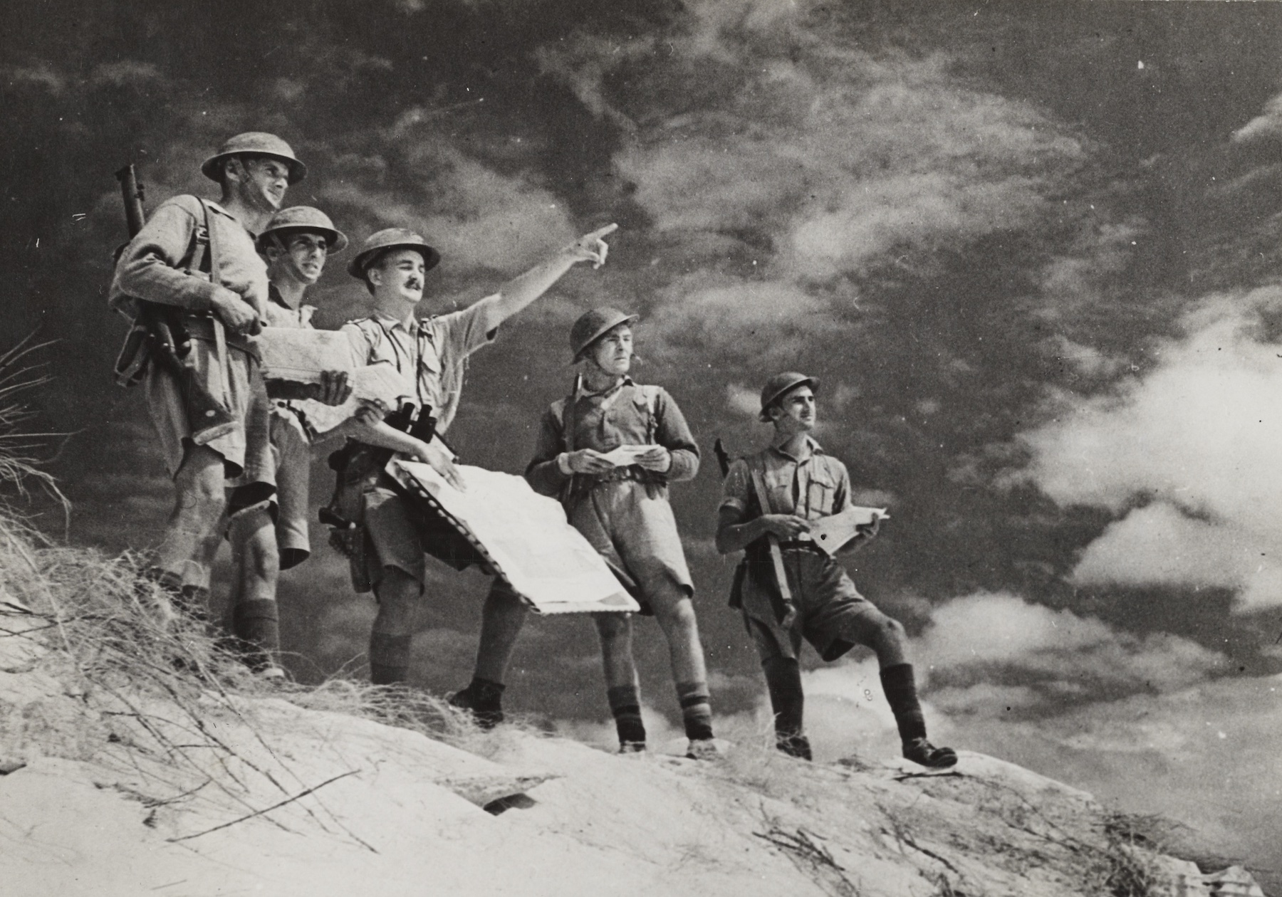 British soldiers in the desert studying maps and terrain.